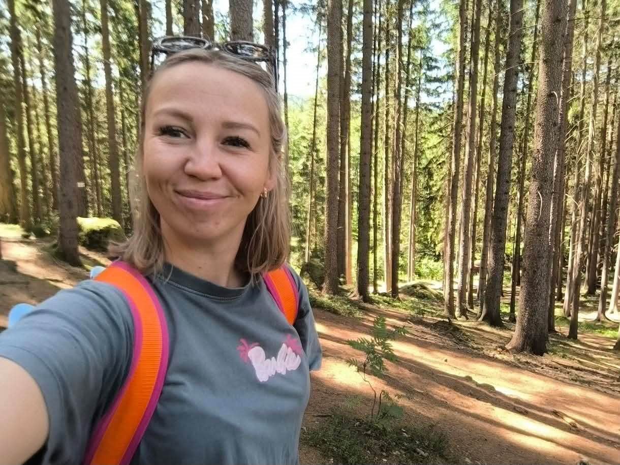 Aleksandra Tanabasz, prowadząca zajęcia, uśmiechnięta na leśnej ścieżce